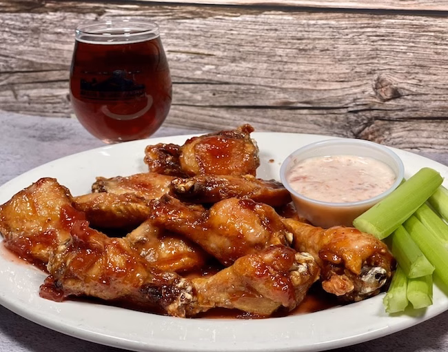 A plate of strawberry chicken wings, paired with strawberry blue cheese dip, celery, and a beer from the Breaker Brewing Outpost (Archbald, PA)
